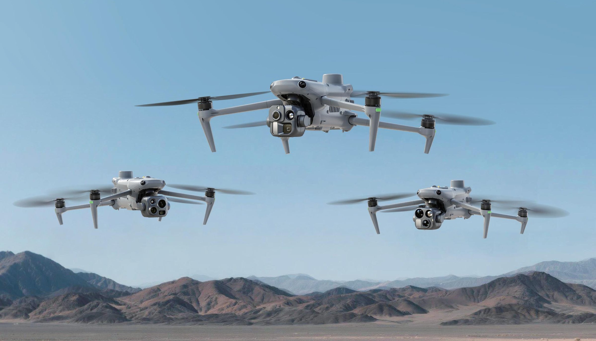 Drei Autel EVO III Multirotor-Drohnen im Formationsflug über einer Bergkette